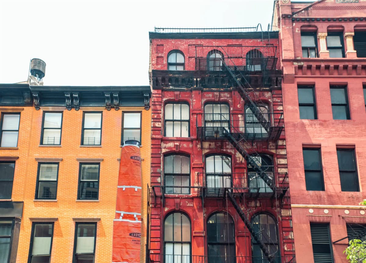 An orange EasyChute trash chute hanging from a brownstone renovation in New York City