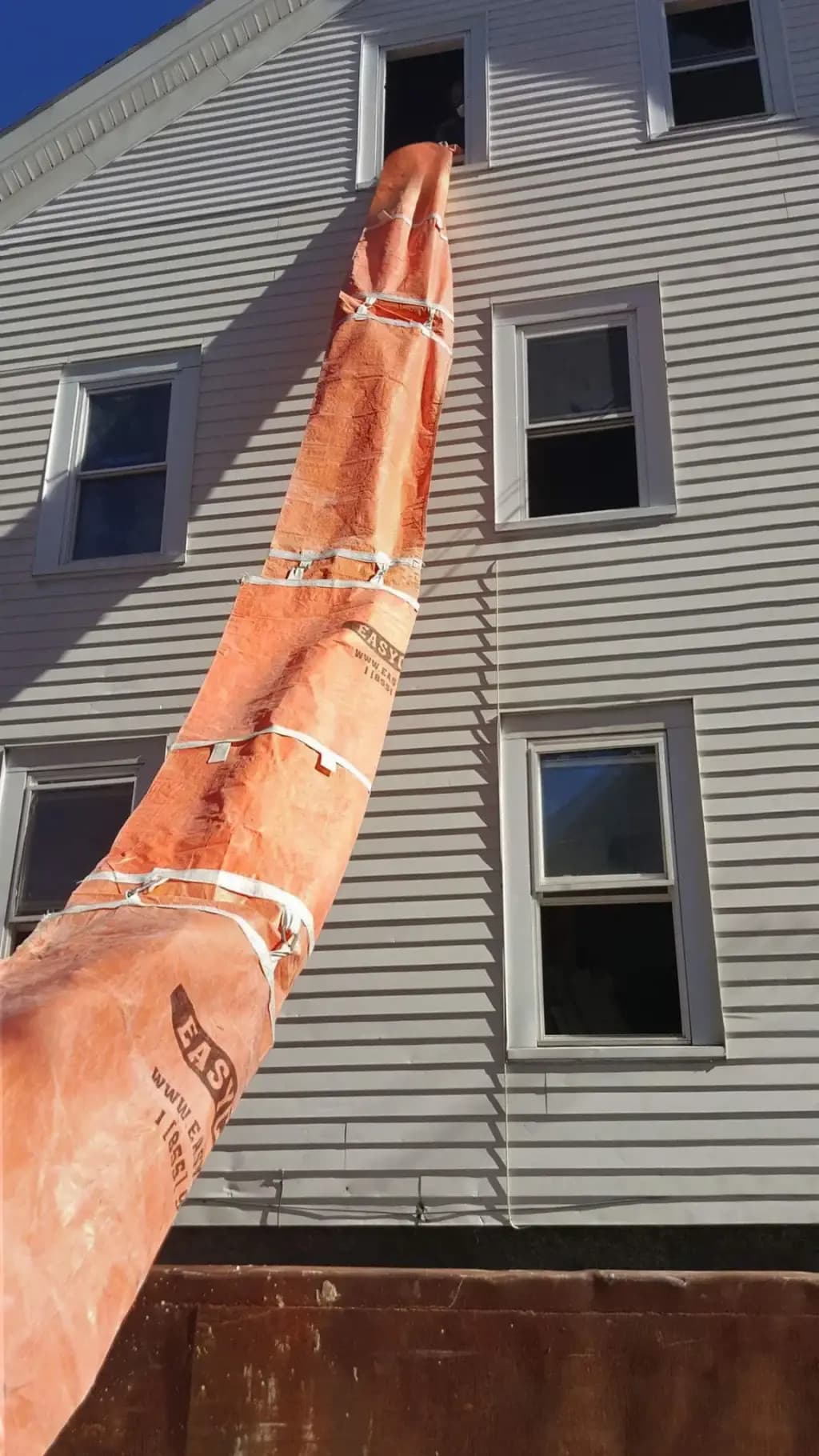 EasyChute heavy-duty trash chute running from a window to a dumpster
